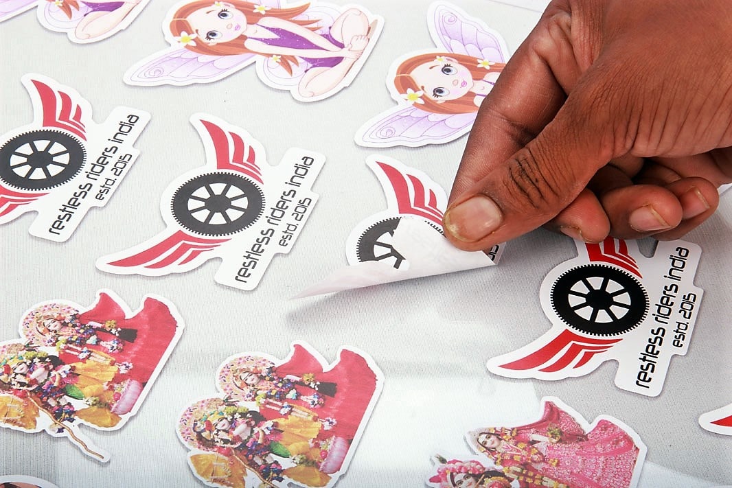 custom kiss cut vinyl stickers digitally printed and cut on the edges in the shape of the design with one of the labels being raised by a hand