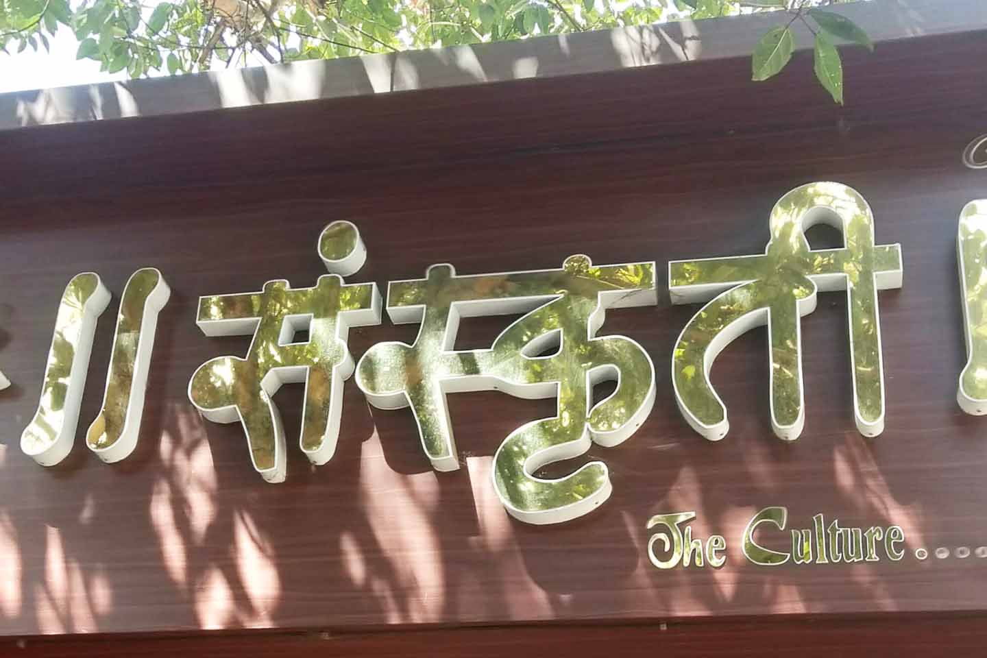 Metal sign board made of gold finish letters fixed on top of laser cut 3D acrylic letters . Shop name board mounted on top of aluminium composite panel