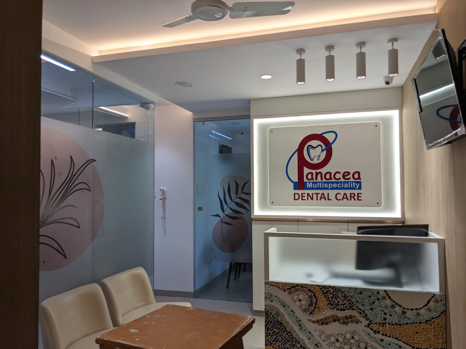 Acrylic logo plate lit from behind with strip LEDs mounted in the reception area of Panacea dental clinic