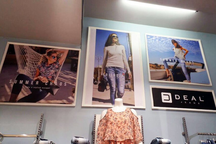 Advertising and brand promotion being done in a retail clothing store by pasting sunboard and vinyl prints on the wall