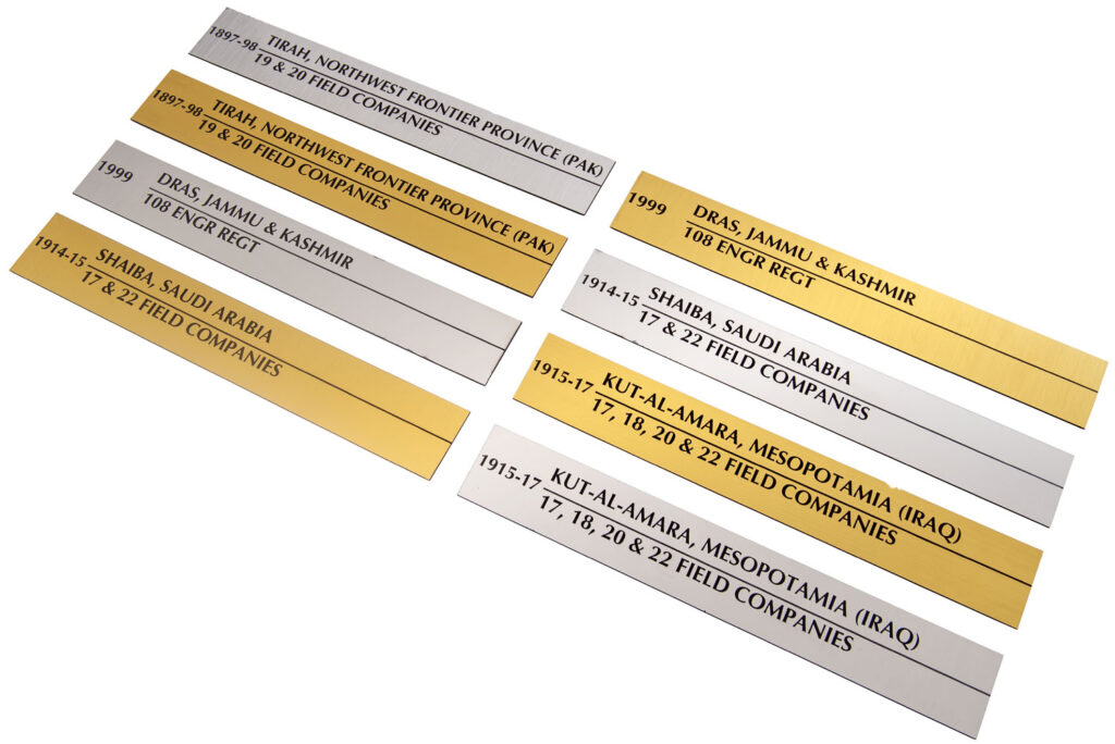 multiple gold and silver laser engraved custom metal name plates laid out